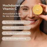 Eine Frau hält eine halbe Zitronenhälfte in der Hand plus Produktinformationen zu Vitamin C Shot 1.000 mg
