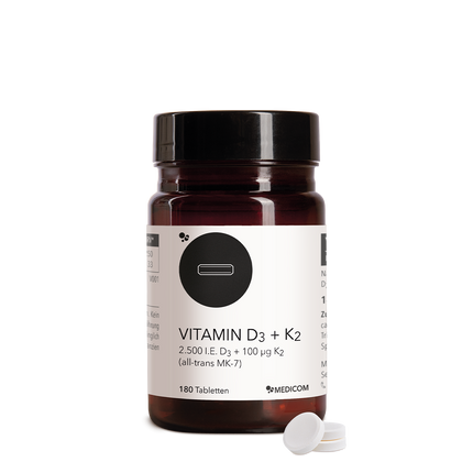Die Produktdose von Vitamin D3 + K2 Tabletten und drei Tabletten im Vordergrund