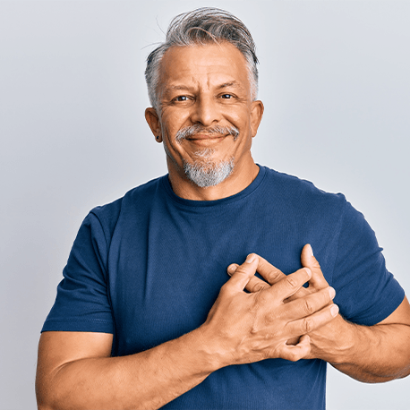 Ein Mann mittleren Alters hält sich mit den Händen an das Herz