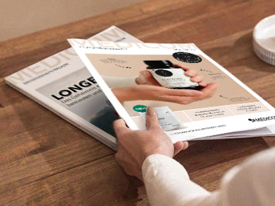 Eine Frauenhand hält das Gesundheits-Magazin und ein Produktkatalog in der Hand