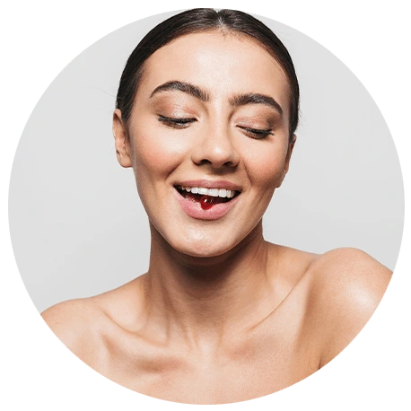 Frau mit geglättetem Haar, die mit geschlossenen Augen lächelt, mit nackten Schultern, vor einem hellen Hintergrund.