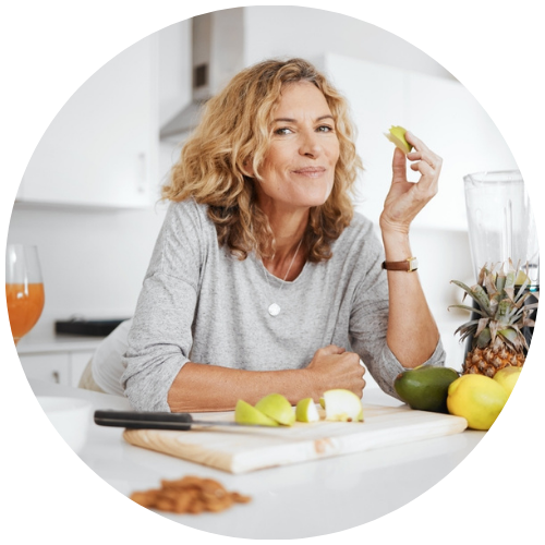 Blonde Frau in mittlerem Alter mit Schneidebrett mit Obst und zufriedenem Lächeln