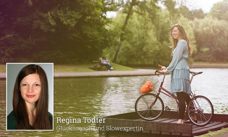 Frau mit Fahrrad an einem Flussufer