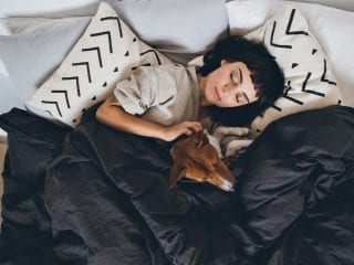 Junge Frau im Bett mit Hund