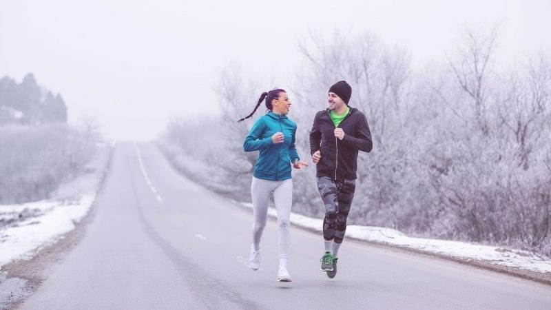 Ein Paar läuft auf einer Straße in einer Winterlandschaft