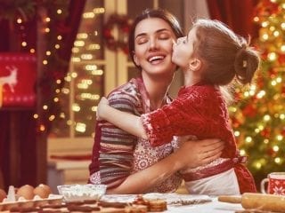 Kleine Tochter küsst Mutter zu Weihnachten