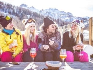 Skifahrerinnen sitzen in der Gruppe zusammen und trinken zusammen
