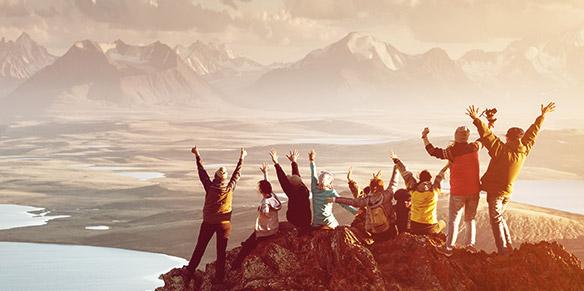 Auf den Berggipfeln jubeln junge Menschen und erfreuen sich an dem  Sonnenaufgang
