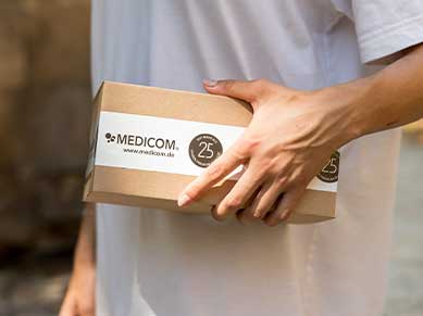 Ein Paketzustellter hält ein Medicom-Paket in der Hand