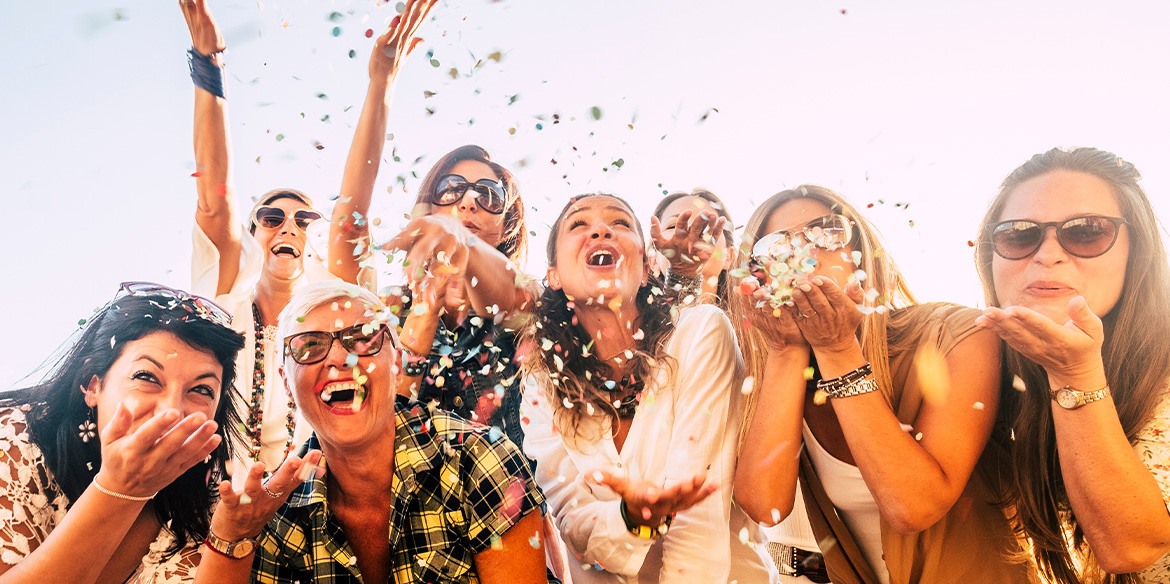 Frauen unterschiedlichen Alters feiern, lachen und werfen zusammen Konfetti