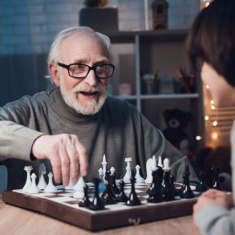 Ein älterer Mann mit Bart und Brille beim Schachspielen