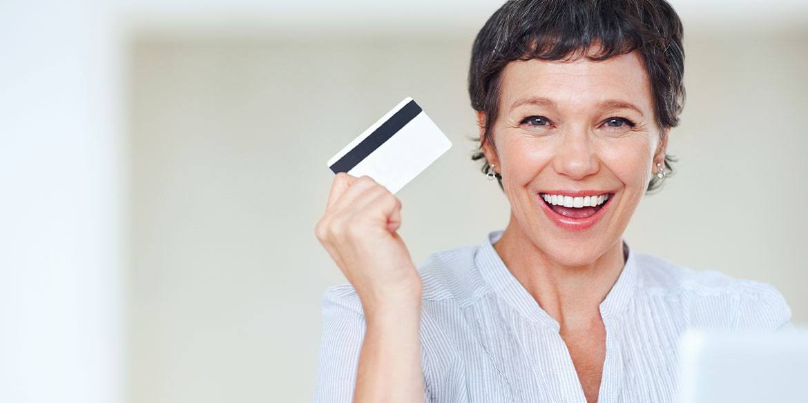 Eine Frau lacht in die Kamera. Sie eine Kreditkarte in der Hand