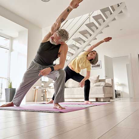 Eine Frau und ein Mann auf Yogamatten bei einer Dehnübung