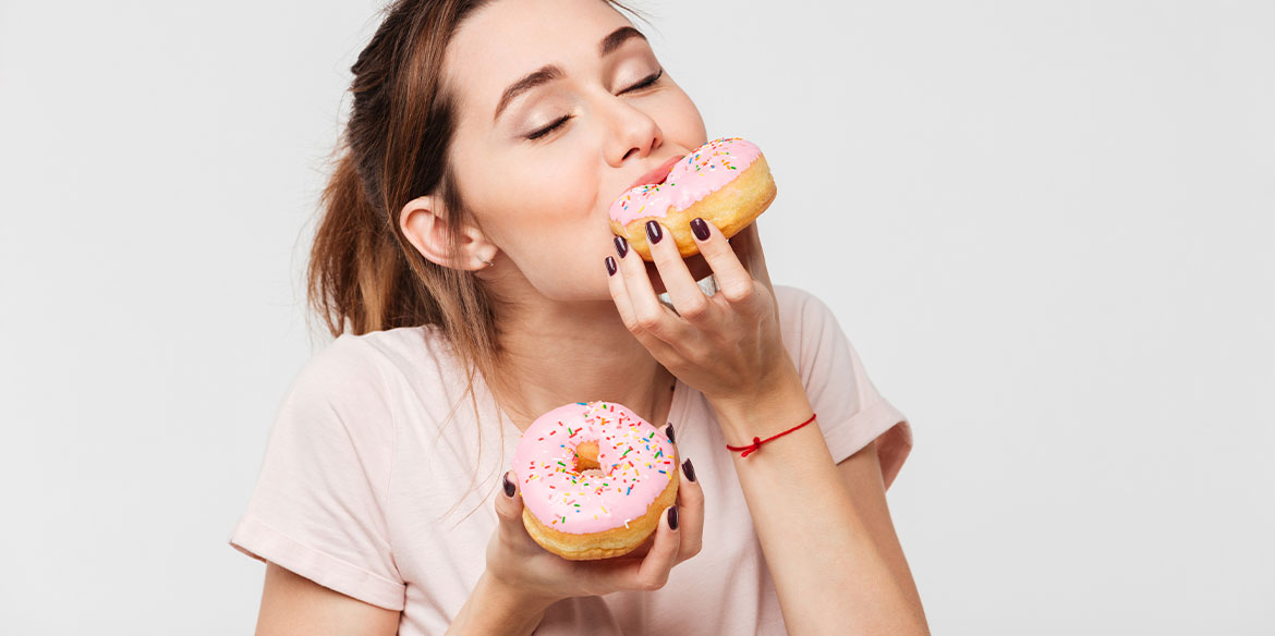 Eine junge Frau hat eine Heißhungerattacke und verschlingt Donuts