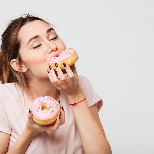 Eine junge Frau hat eine Heißhungerattacke und verschlingt Donuts