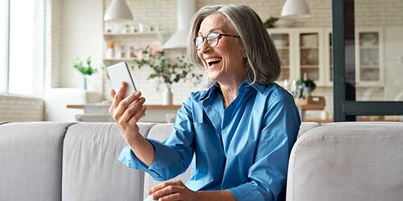 Eine Frau schaut auf ihr Smartphone und lacht