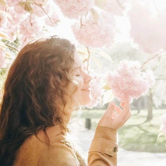Eine junge Frau riecht an einer rosa Blüte