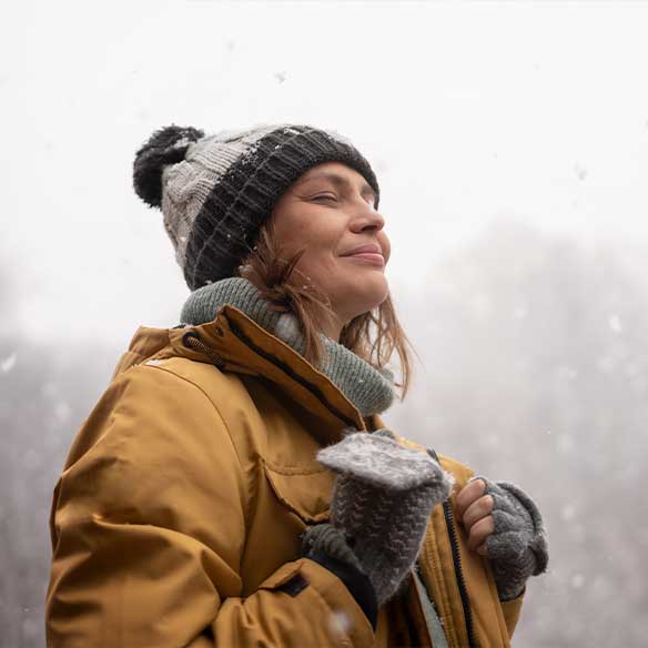 Eine Frau mit Pudelmütze im grauen Winterwetter