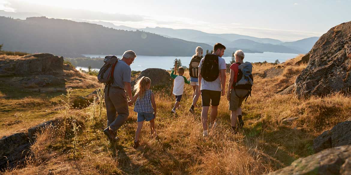 Mehrere Generationen einer Familien gehen auf einem Hügel spazieren.