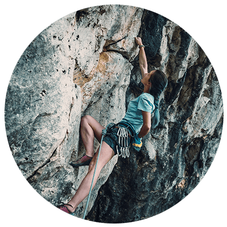 Frau klettert eine Felswand hinauf