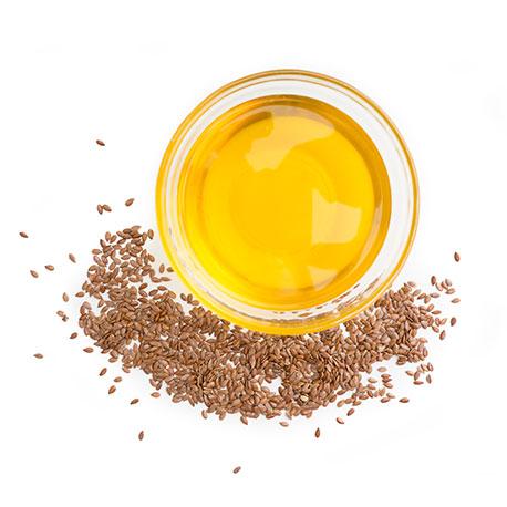 goldenes Leinsamenöl in einer Glasschüssel, mit Leinsamen darum liegend, von oben fotografiert Hormonelle Veränderungen mit Wechseljahre Kapseln unterstützen