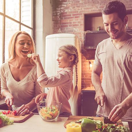 Junge Familie beim Salat schneiden in der Küche. Multivitaminreich ernähren
