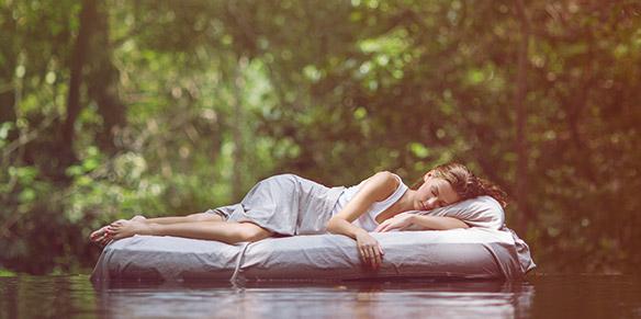 Eine Frau liegt auf einer Matratze im Wasser und schläft