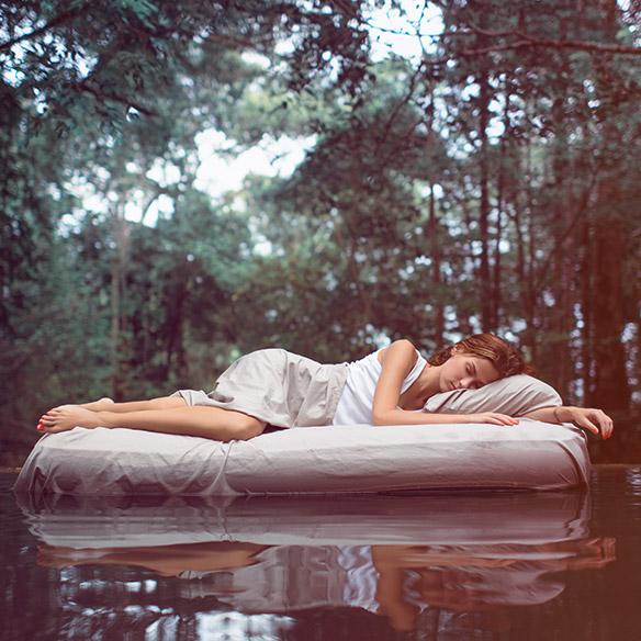 Frau liegt im Paradies in einem See auf einer Matratze und schläft