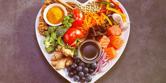Teller in Herzform gefüllt mit gesundem Obst und Gemüse