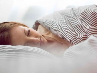 Eine Frau schläft in gestreifter Bettwäsche